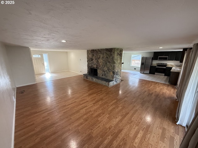 unfurnished living room with a textured ceiling, a fireplace, and light hardwood / wood-style flooring