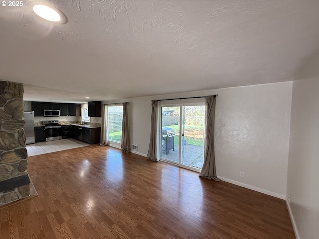 unfurnished living room with a textured ceiling, light wood-type flooring, and sink