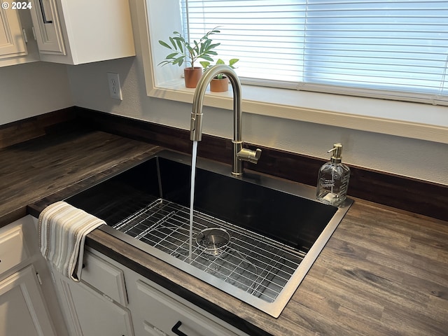 room details featuring sink, white cabinets, and wood counters