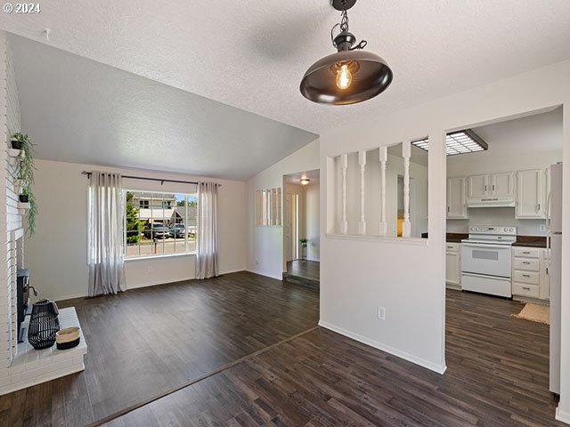 unfurnished living room with lofted ceiling, dark hardwood / wood-style floors, and a brick fireplace