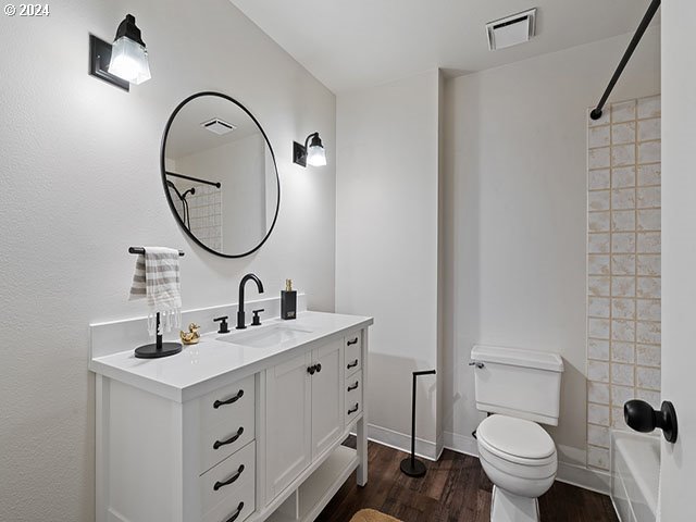 full bathroom featuring toilet, shower / bath combination, hardwood / wood-style flooring, and vanity