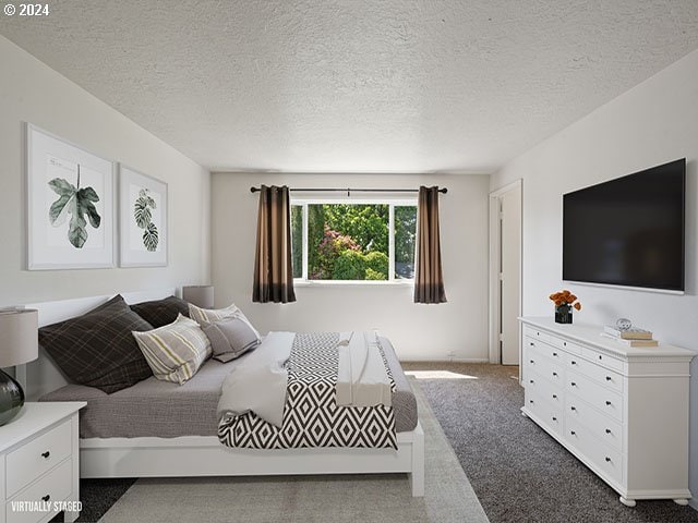 bedroom with a textured ceiling and dark colored carpet