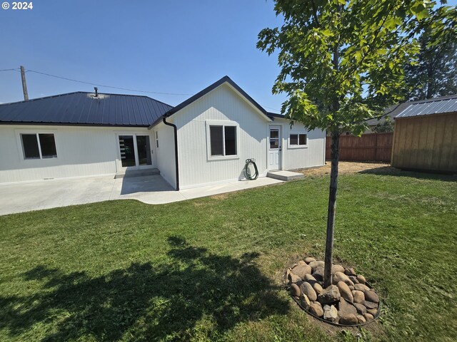 back of property with a yard and a patio area