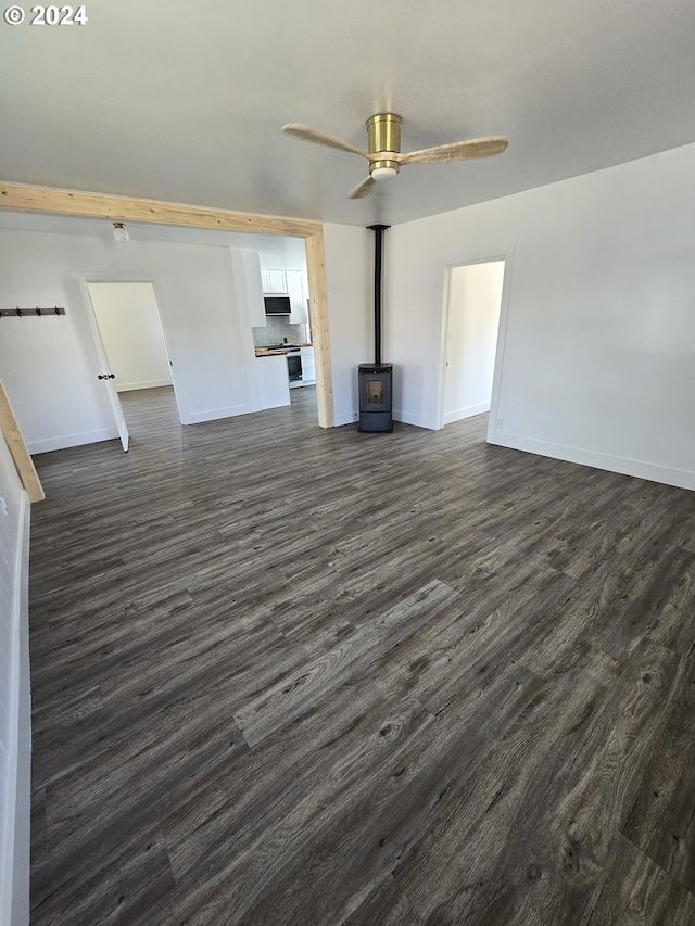 unfurnished living room with dark hardwood / wood-style floors, ceiling fan, and a wood stove