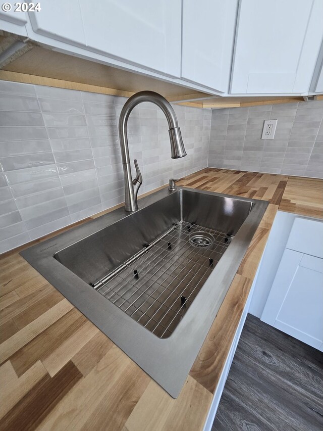 details with sink, backsplash, dark hardwood / wood-style floors, and white cabinets