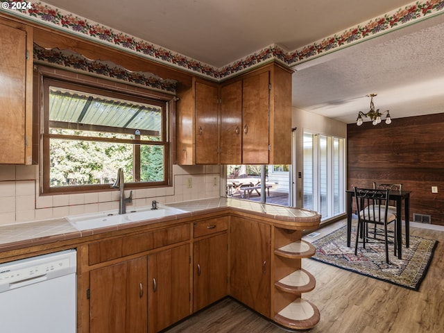 kitchen featuring tile countertops, dishwasher, sink, dark hardwood / wood-style flooring, and kitchen peninsula