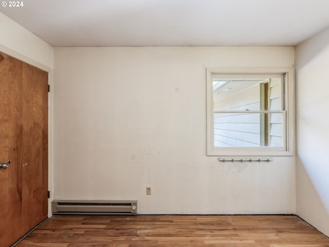 spare room featuring a baseboard heating unit and hardwood / wood-style floors