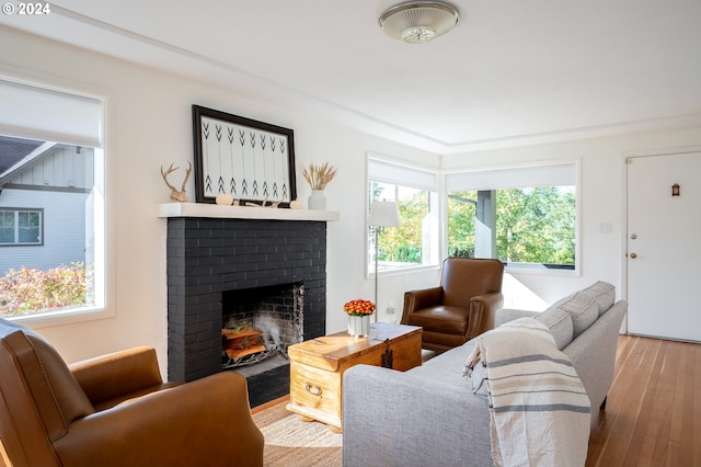 living room with a brick fireplace, light wood-type flooring, and a wealth of natural light