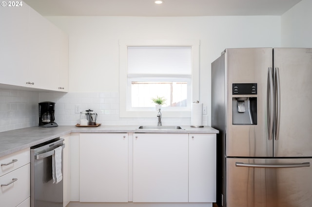 kitchen featuring appliances with stainless steel finishes, white cabinetry, sink, and backsplash