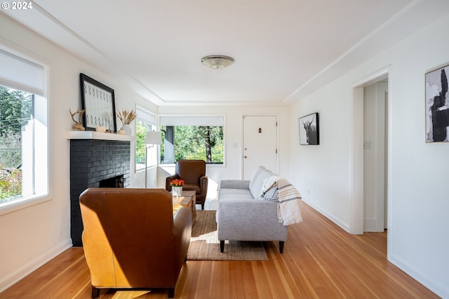 living room featuring a brick fireplace and light wood-type flooring