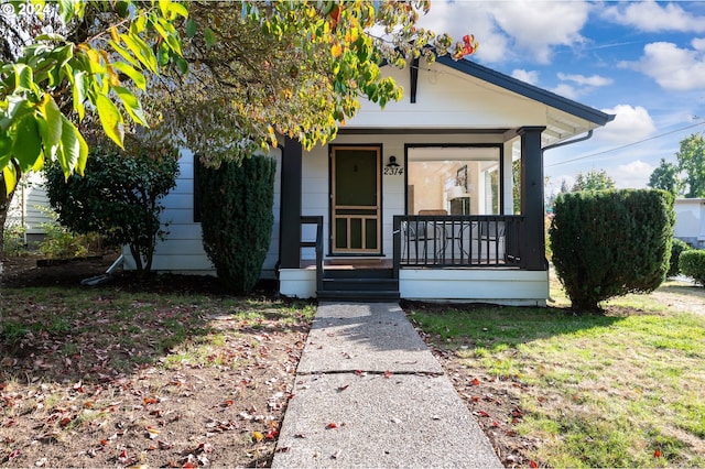 bungalow-style home featuring covered porch and a front yard