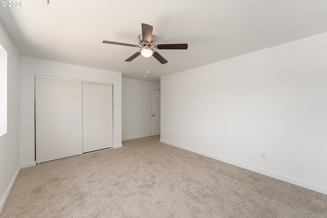 unfurnished bedroom featuring light carpet, a closet, and ceiling fan