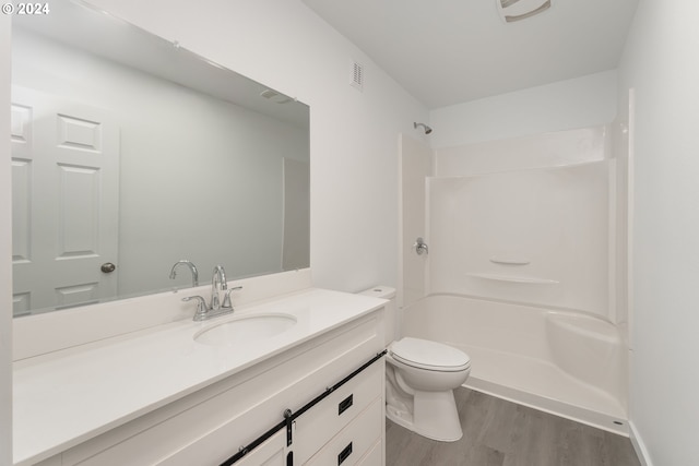 bathroom with hardwood / wood-style floors, vanity, toilet, and walk in shower