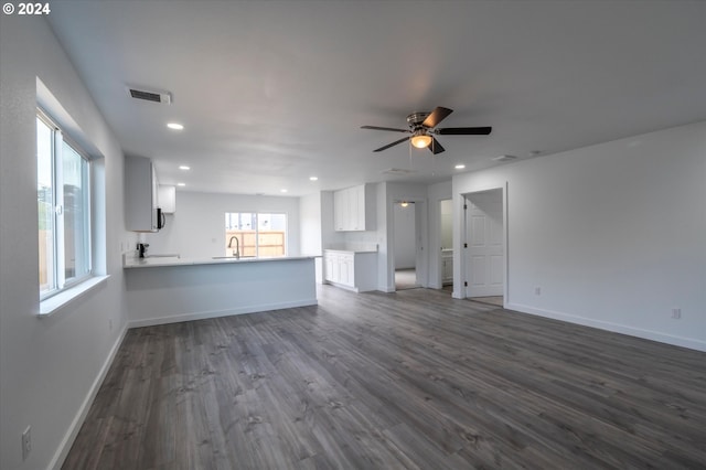 unfurnished living room featuring ceiling fan, a healthy amount of sunlight, and dark hardwood / wood-style floors