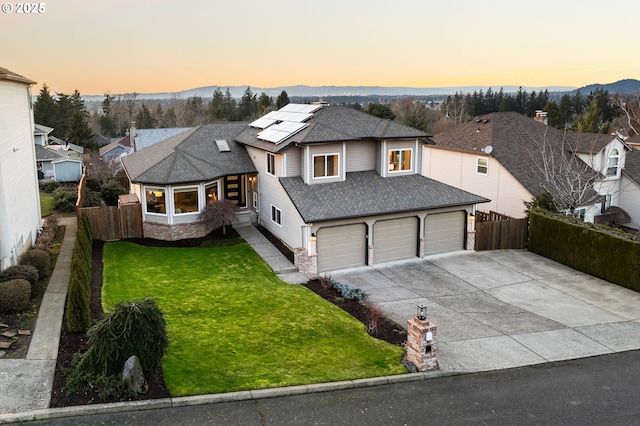 view of front of house featuring a garage, a yard, and solar panels