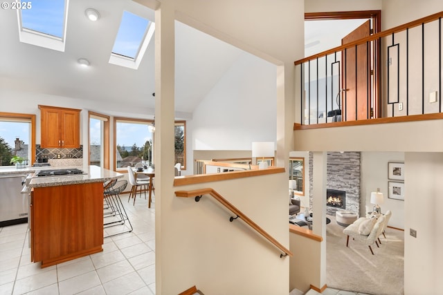 stairway featuring a stone fireplace, a skylight, tile patterned floors, and a healthy amount of sunlight