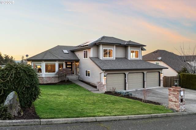 view of front of house featuring a garage, a yard, and solar panels