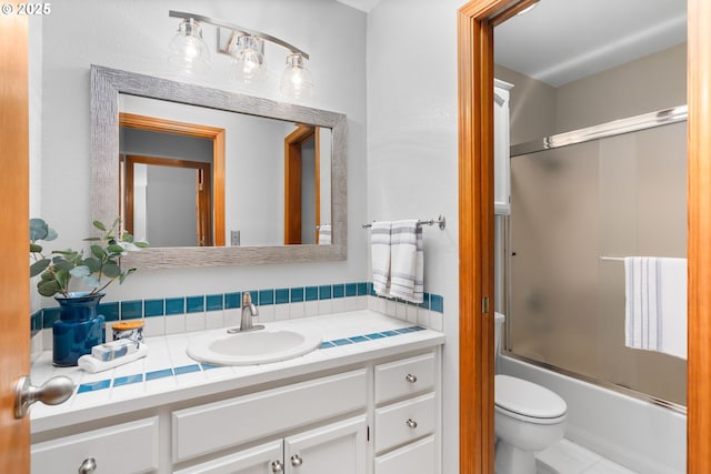 full bathroom featuring enclosed tub / shower combo, vanity, and toilet