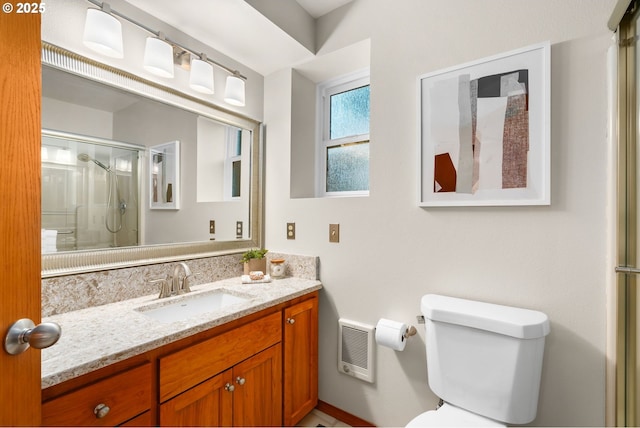 bathroom with vanity, toilet, and a shower with door