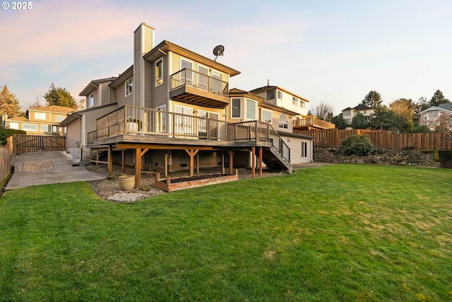 back house at dusk featuring a yard, a patio area, and a deck