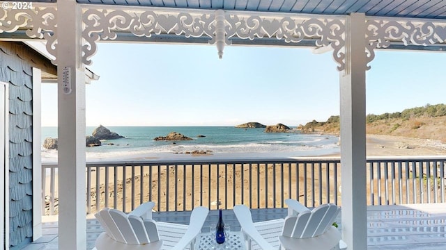 wooden terrace featuring a water view and a beach view