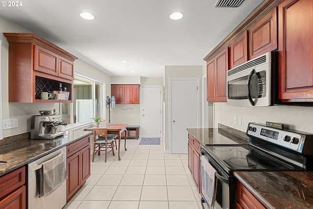 kitchen featuring light tile patterned flooring, dark stone countertops, and appliances with stainless steel finishes