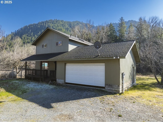 view of front facade with a garage, a mountain view, and covered porch