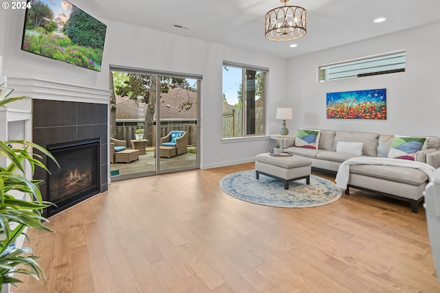 living room with a notable chandelier, light wood-type flooring, and a fireplace