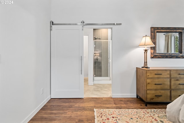 bedroom with hardwood / wood-style floors, a barn door, and ensuite bathroom