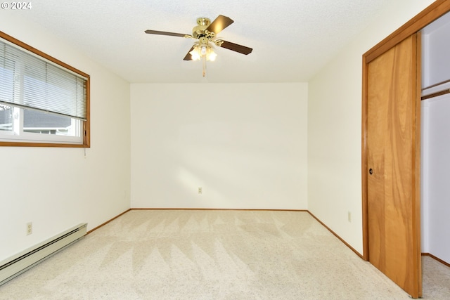 unfurnished bedroom featuring ceiling fan, a textured ceiling, a baseboard heating unit, light colored carpet, and a closet