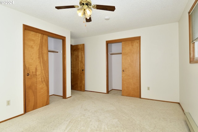 unfurnished bedroom with light colored carpet, a textured ceiling, and two closets