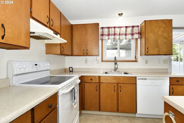 kitchen featuring white appliances, sink, light tile patterned floors, and a textured ceiling