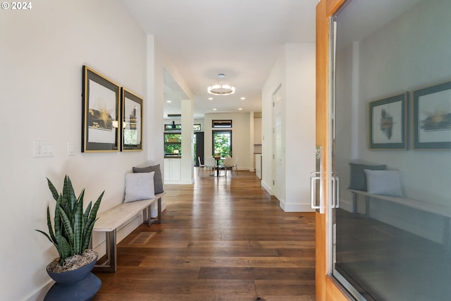 corridor with a chandelier and dark hardwood / wood-style floors