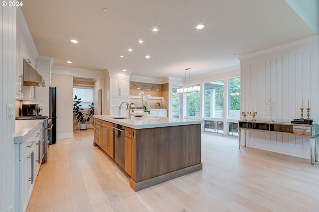 kitchen with stainless steel appliances, a center island with sink, sink, white cabinetry, and light hardwood / wood-style floors