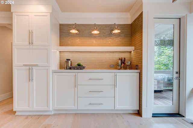 bar with white cabinetry, hanging light fixtures, and light wood-type flooring