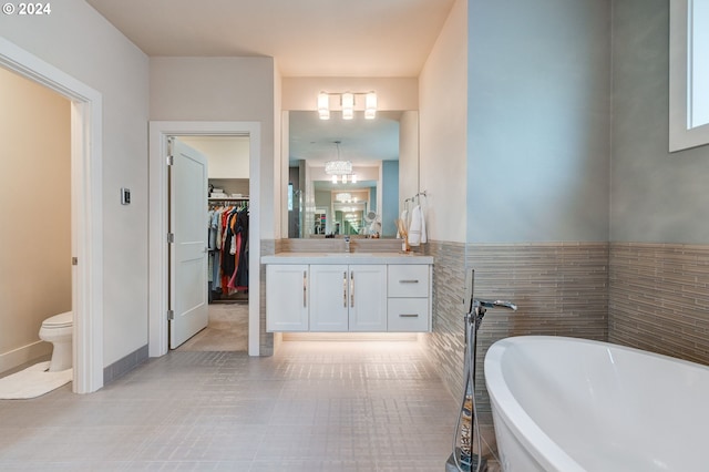 bathroom with toilet, tile patterned flooring, a bathtub, vanity, and tile walls