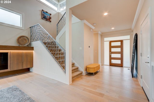 foyer entrance featuring crown molding and light wood-type flooring