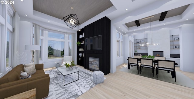 living room with a fireplace, a raised ceiling, light hardwood / wood-style floors, and a chandelier