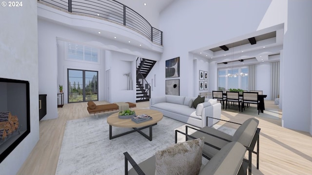 living room with light hardwood / wood-style flooring, a notable chandelier, and a towering ceiling