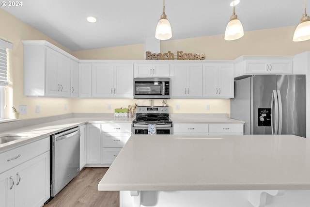 kitchen with pendant lighting, light hardwood / wood-style flooring, stainless steel appliances, and vaulted ceiling