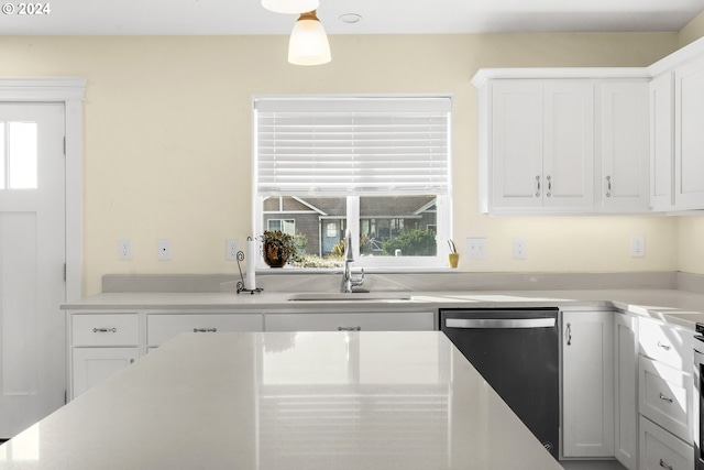 kitchen with hanging light fixtures, white cabinetry, sink, and stainless steel dishwasher