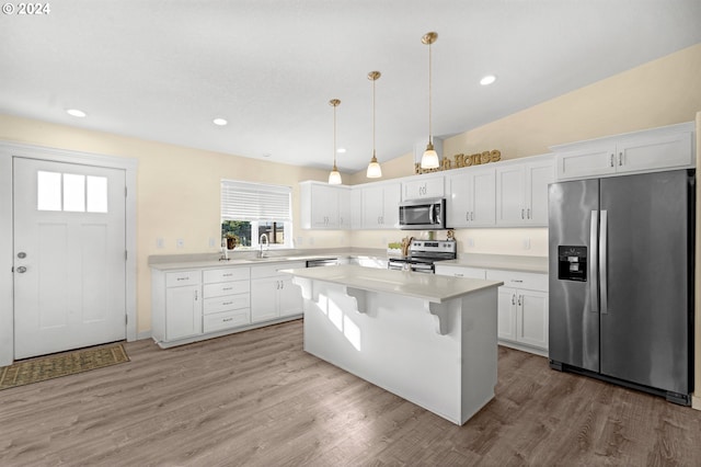 kitchen with stainless steel appliances, white cabinetry, hanging light fixtures, and lofted ceiling