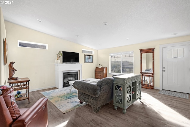 living room with a textured ceiling, vaulted ceiling, and hardwood / wood-style flooring