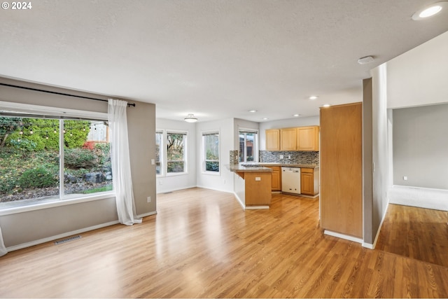 kitchen featuring decorative backsplash, a kitchen bar, dishwasher, a center island, and light hardwood / wood-style floors