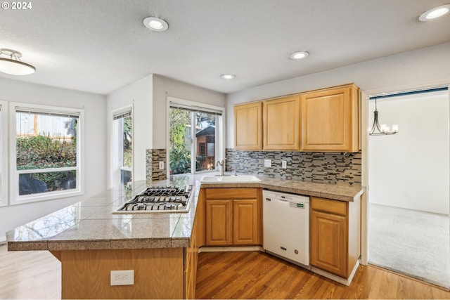 kitchen featuring dishwasher, kitchen peninsula, stainless steel gas stovetop, and sink