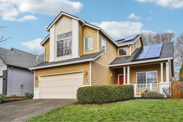 view of front of property featuring solar panels, a porch, a garage, and a front yard