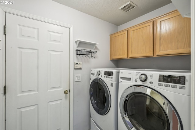 laundry area with cabinets, separate washer and dryer, and a textured ceiling