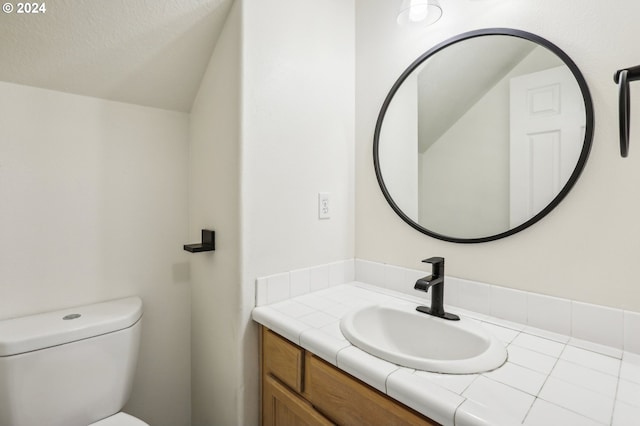 bathroom with vanity, toilet, and a textured ceiling