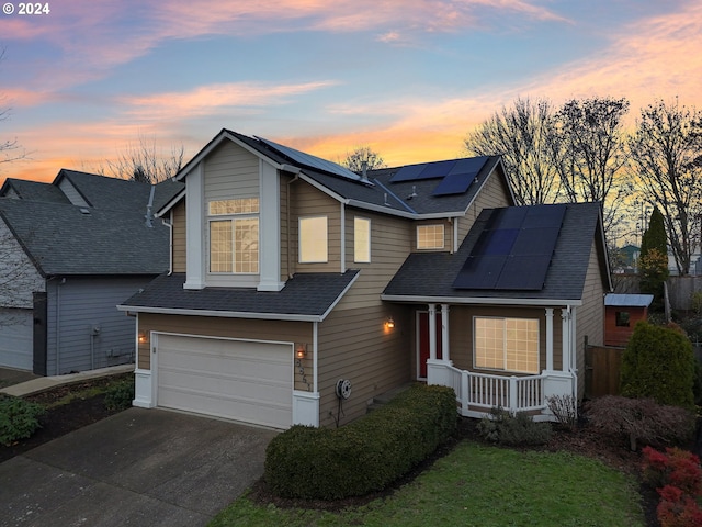 view of front facade with covered porch, solar panels, and a garage