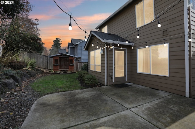 back house at dusk featuring a patio area and a lawn